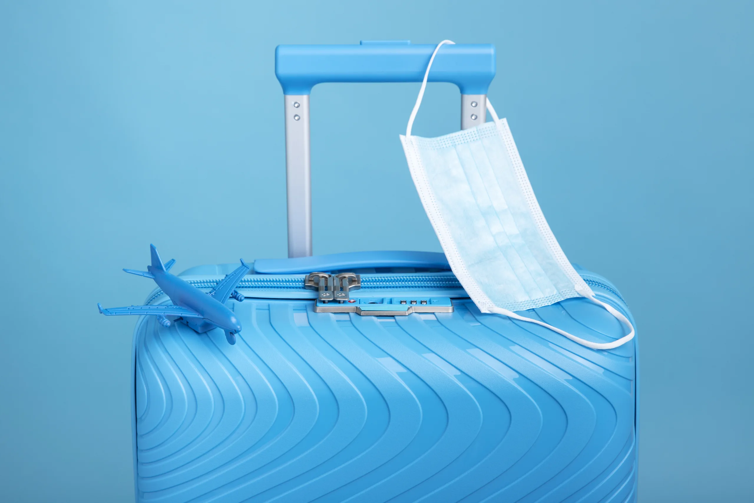 blue-suitcase-travel-with-medical-mask representing Global Medical Tourism.